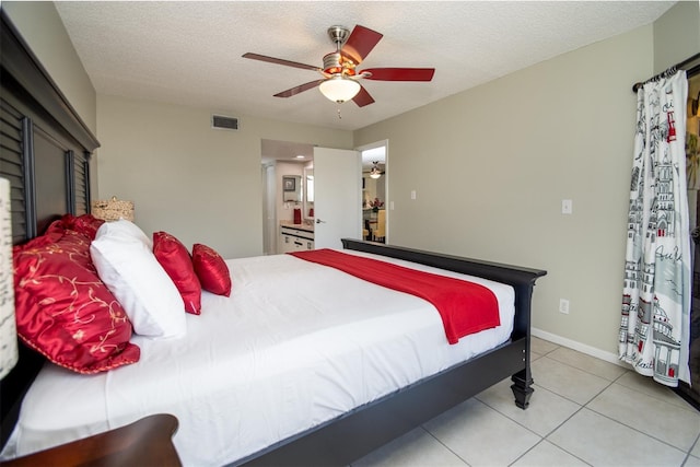 bedroom featuring ceiling fan, ensuite bath, a textured ceiling, and light tile patterned floors