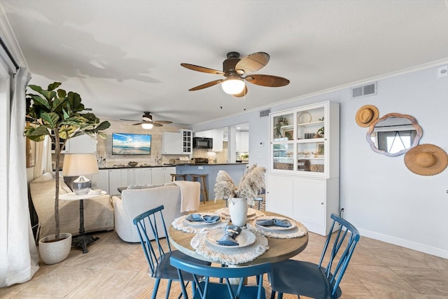 tiled dining space with ceiling fan and ornamental molding