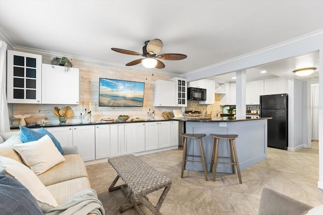 kitchen with white cabinetry, decorative backsplash, a kitchen island, black appliances, and ornamental molding