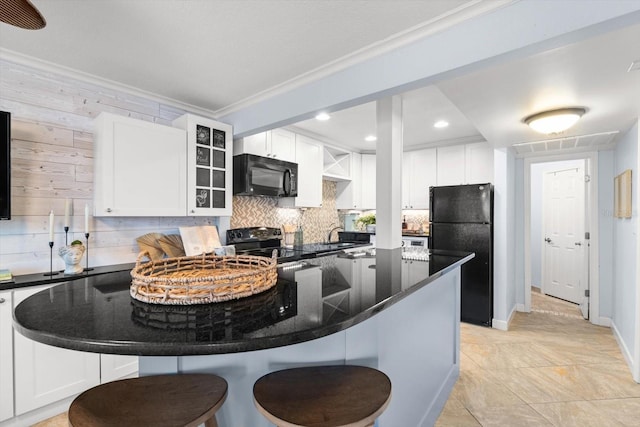 kitchen featuring a breakfast bar area, decorative backsplash, white cabinets, black appliances, and ornamental molding