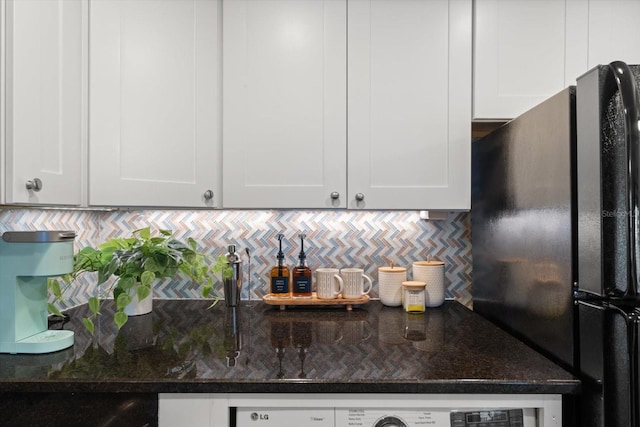 kitchen featuring white cabinets, black refrigerator, and dark stone counters