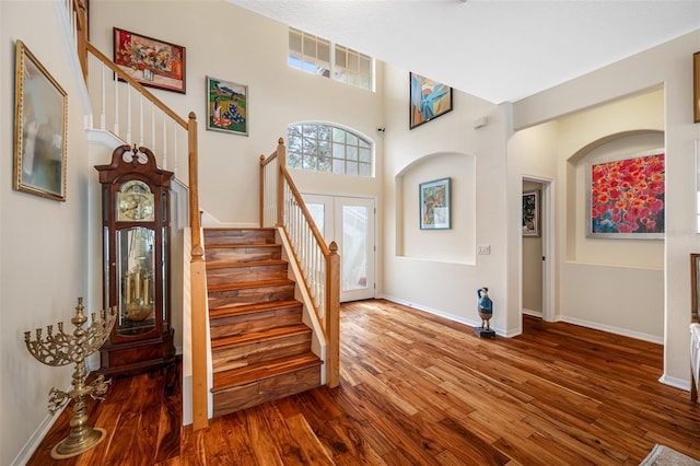 entryway with wood-type flooring, a high ceiling, and french doors