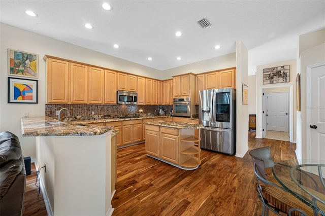 kitchen featuring light brown cabinets, dark hardwood / wood-style flooring, kitchen peninsula, and stainless steel appliances