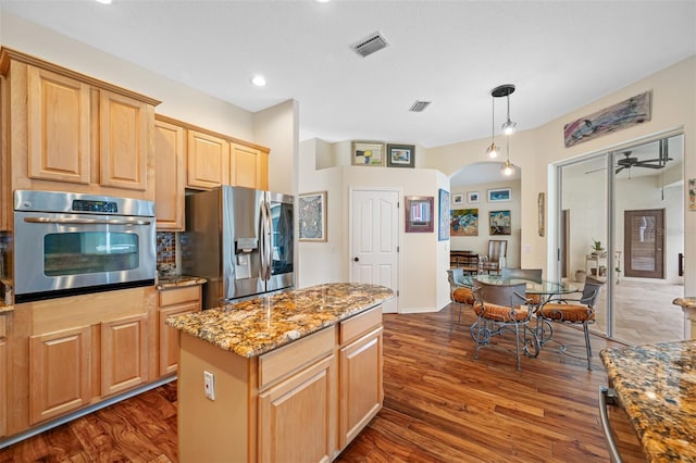 kitchen with a center island, ceiling fan, dark hardwood / wood-style floors, appliances with stainless steel finishes, and light stone counters