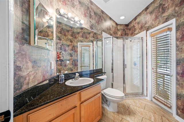 bathroom with a shower with door, vanity, and toilet