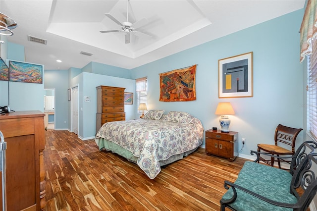 bedroom with ceiling fan, wood-type flooring, and a tray ceiling