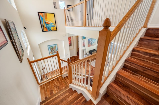 stairway with a high ceiling and hardwood / wood-style flooring