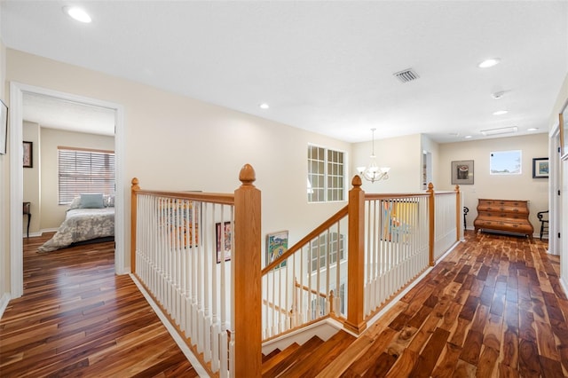 hallway with dark hardwood / wood-style flooring and an inviting chandelier