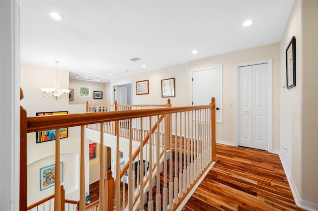 hallway featuring wood-type flooring and a notable chandelier