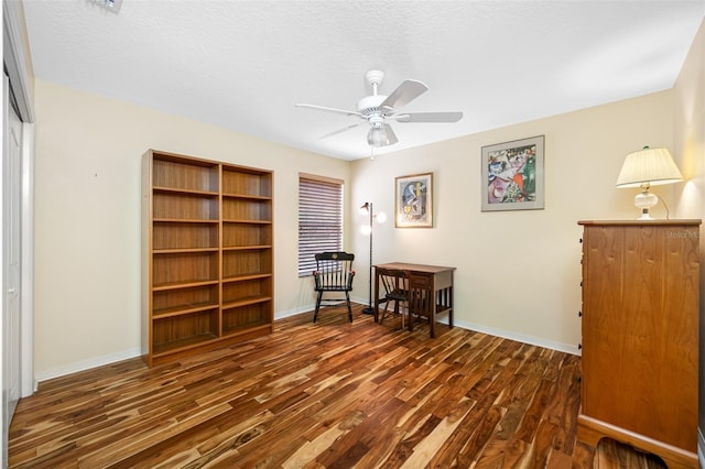 interior space featuring a textured ceiling, ceiling fan, and dark wood-type flooring