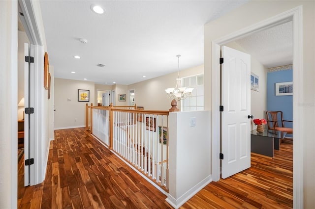 hallway with a chandelier, dark wood-type flooring, and a textured ceiling