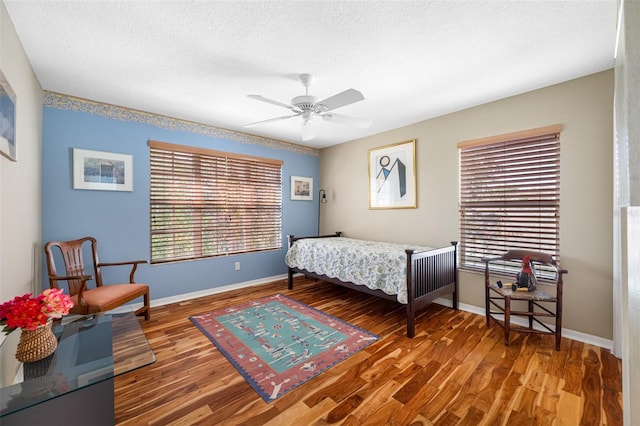 bedroom featuring ceiling fan, wood-type flooring, and a textured ceiling