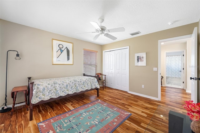 bedroom with a textured ceiling, a closet, hardwood / wood-style flooring, and ceiling fan