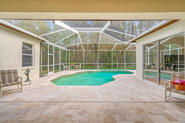 view of pool with glass enclosure and a patio