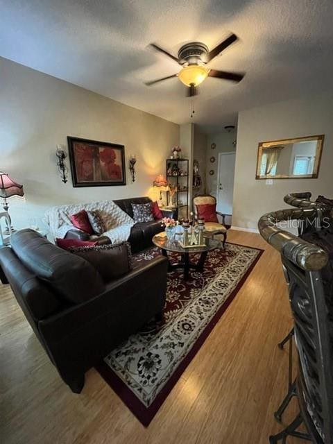 living room featuring ceiling fan, hardwood / wood-style floors, and a textured ceiling