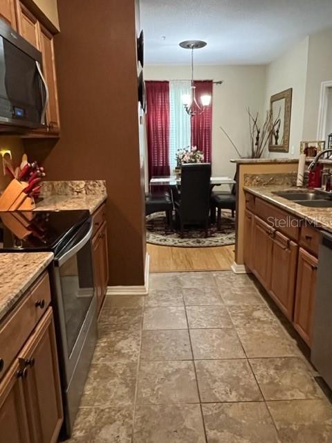 kitchen featuring light stone counters, sink, decorative light fixtures, and appliances with stainless steel finishes