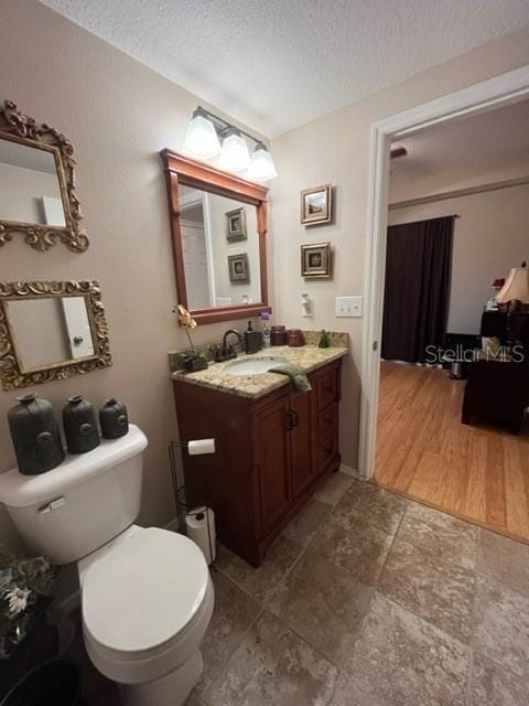 bathroom with vanity, a textured ceiling, and toilet