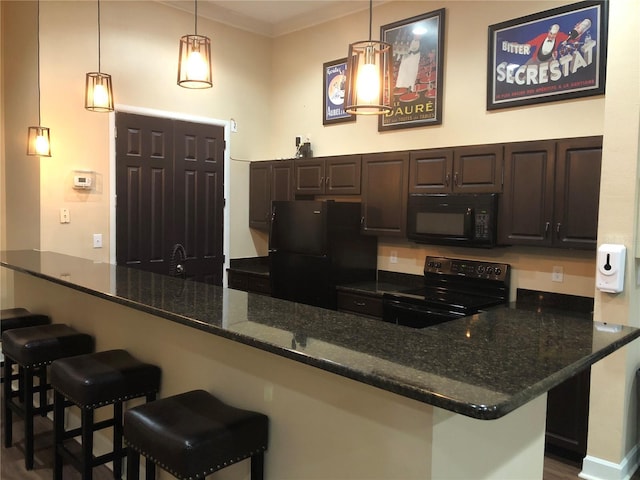 kitchen featuring a kitchen breakfast bar, dark brown cabinetry, hanging light fixtures, and black appliances