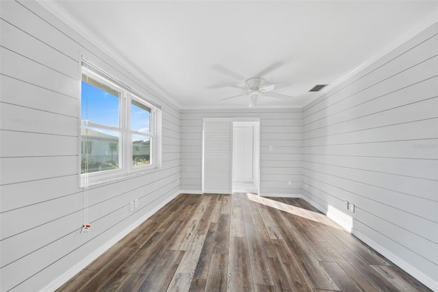 empty room featuring dark hardwood / wood-style floors, ceiling fan, ornamental molding, and wooden walls