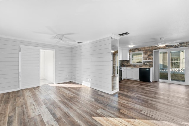 unfurnished living room with wood walls, wood-type flooring, and ornamental molding