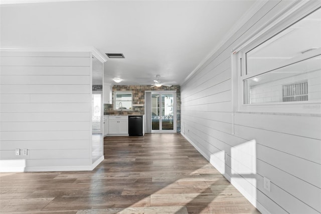 interior space with ceiling fan, sink, crown molding, hardwood / wood-style floors, and wooden walls