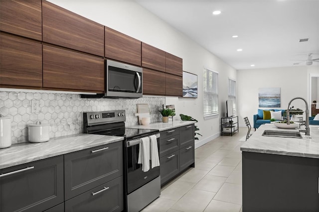 kitchen featuring ceiling fan, sink, appliances with stainless steel finishes, and tasteful backsplash