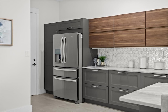 kitchen with decorative backsplash, light stone counters, light tile patterned floors, and stainless steel refrigerator with ice dispenser