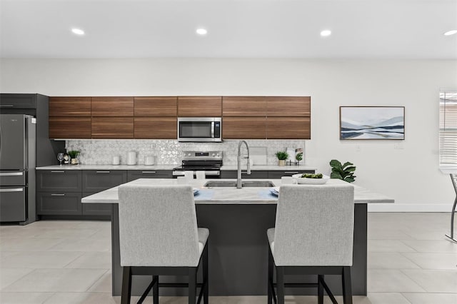 kitchen featuring a kitchen bar, appliances with stainless steel finishes, and a kitchen island with sink