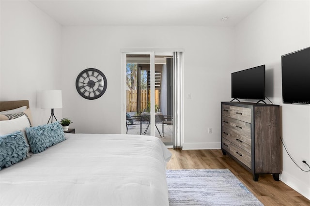 bedroom with access to exterior and hardwood / wood-style floors