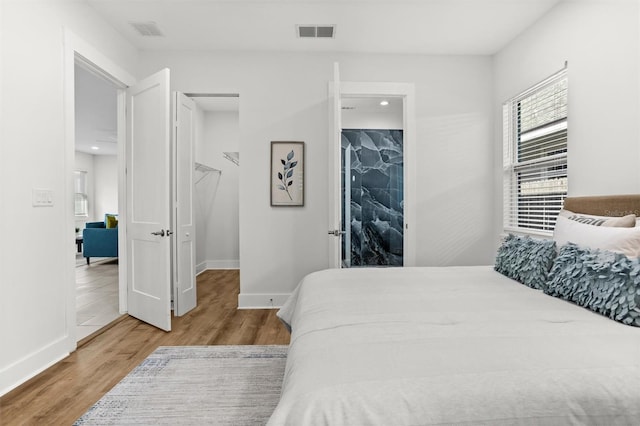 bedroom with a walk in closet, a closet, and hardwood / wood-style flooring