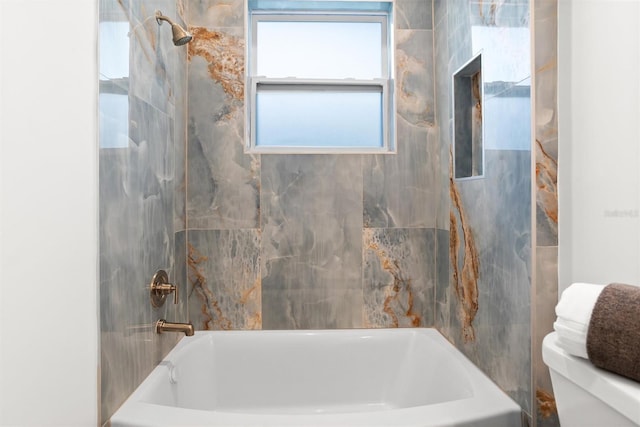 bathroom with toilet and tiled shower / bath