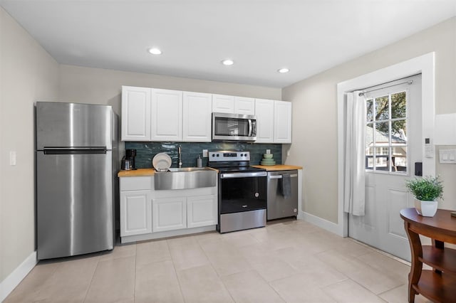 kitchen with wooden counters, white cabinets, sink, decorative backsplash, and appliances with stainless steel finishes