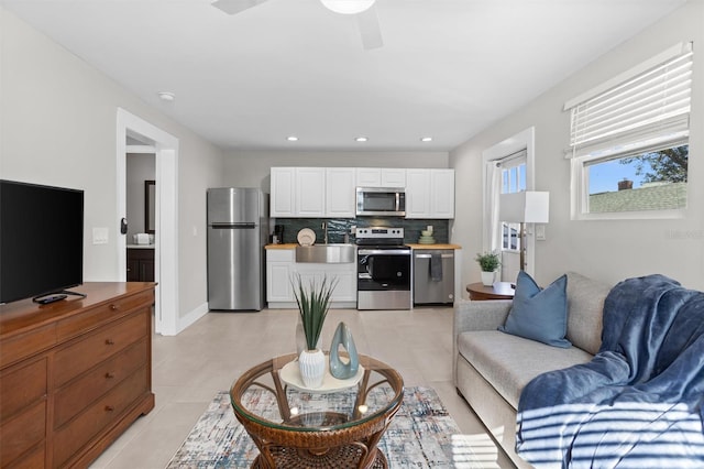 living room with ceiling fan, light tile patterned floors, and sink