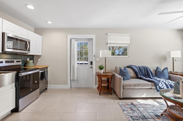 kitchen featuring butcher block counters, white cabinetry, stainless steel appliances, tasteful backsplash, and light tile patterned floors