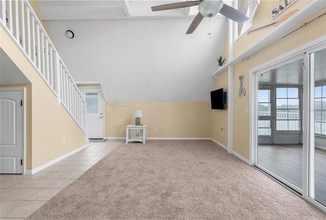 unfurnished living room featuring ceiling fan, high vaulted ceiling, and light carpet