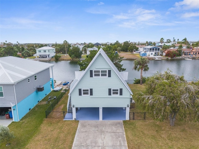 view of front of home featuring an attached garage, concrete driveway, a front lawn, and a water view