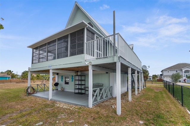 rear view of property with a sunroom, stairway, a lawn, a patio area, and fence