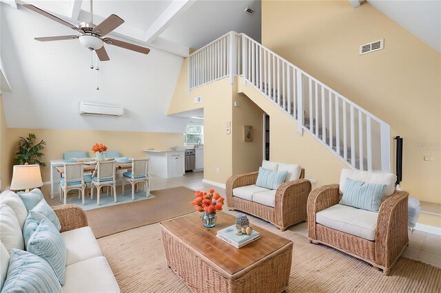 living room with a wall mounted air conditioner, ceiling fan, beamed ceiling, stairway, and high vaulted ceiling