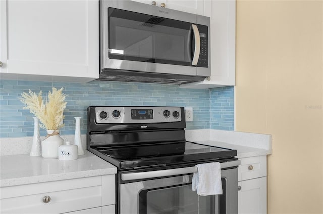 kitchen featuring tasteful backsplash, appliances with stainless steel finishes, light stone counters, and white cabinets