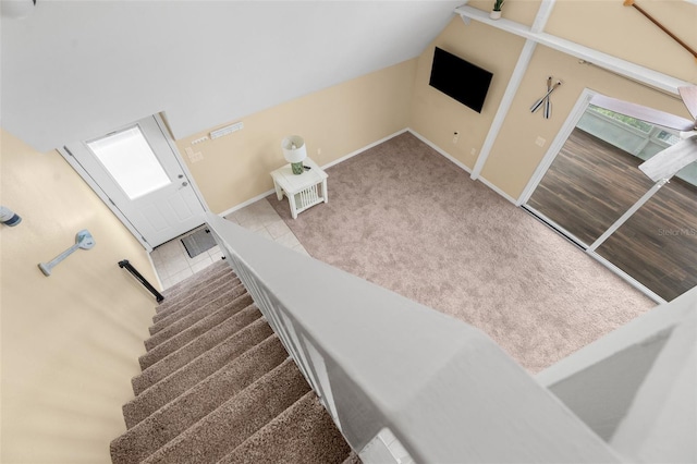 staircase featuring tile patterned floors, carpet flooring, baseboards, and vaulted ceiling