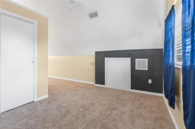 carpeted spare room with baseboards, lofted ceiling, and visible vents