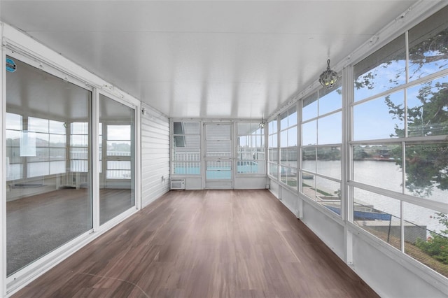 unfurnished sunroom with a wall mounted air conditioner, plenty of natural light, and a water view