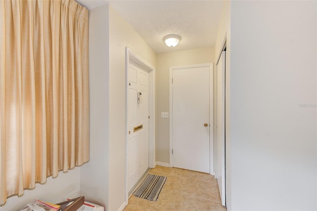 entryway with light tile patterned flooring and a textured ceiling