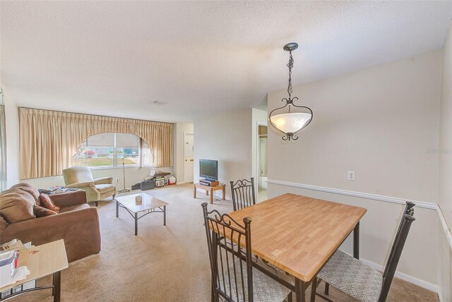 carpeted dining room with a textured ceiling