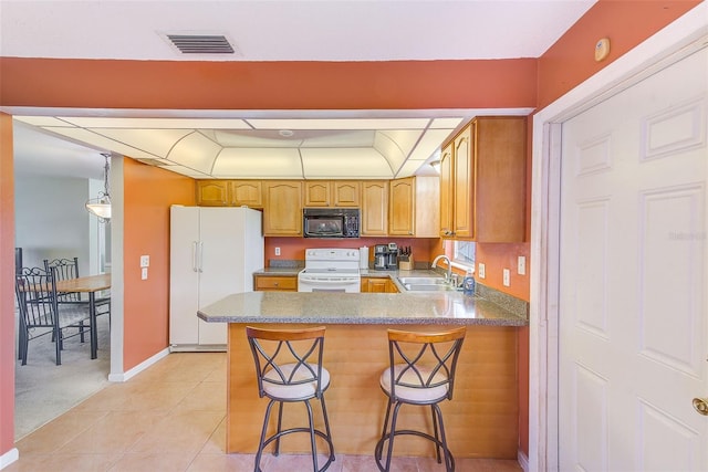 kitchen with kitchen peninsula, a breakfast bar, light tile patterned floors, and white appliances