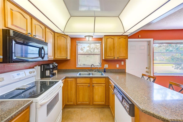 kitchen with light tile patterned floors, white appliances, a healthy amount of sunlight, and sink