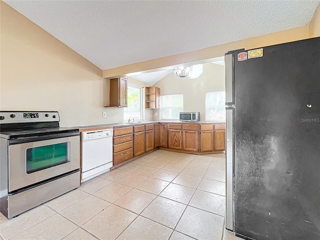 kitchen featuring a textured ceiling, stainless steel appliances, lofted ceiling, and a notable chandelier