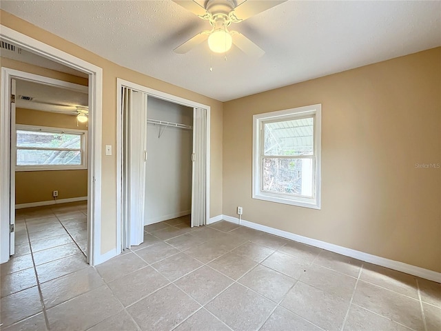 unfurnished bedroom with multiple windows, light tile patterned floors, a closet, and ceiling fan