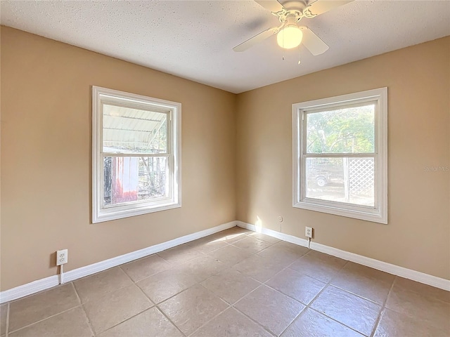 empty room with ceiling fan, light tile patterned floors, and a textured ceiling