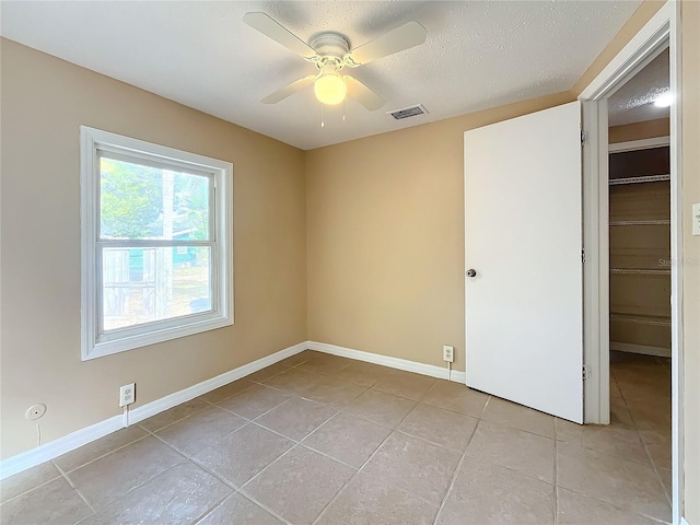 tiled empty room featuring a textured ceiling and ceiling fan